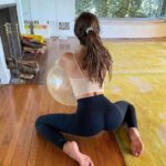 Fitgirl in yoga pants playing around with a yoga ball.